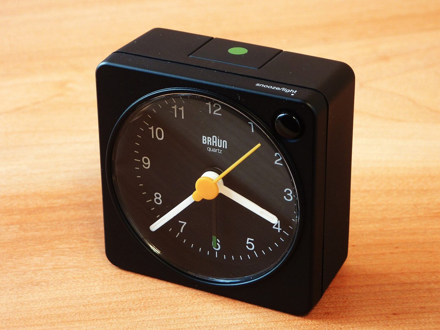 A black Braun BC02X alarm clock on a wooden surface