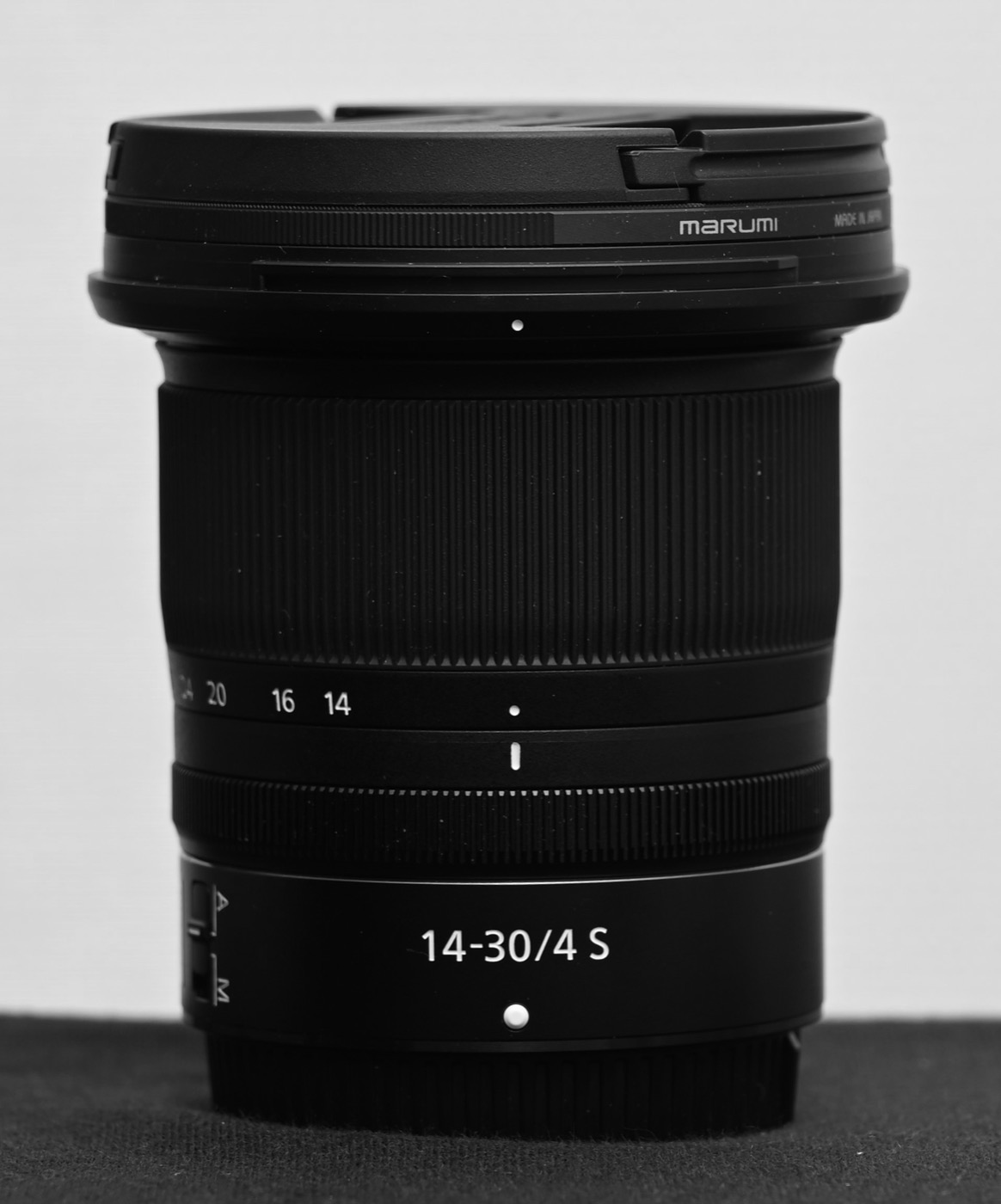 A black Nikon 14-30/4 S lens in black and white, with a filter fitted to the front